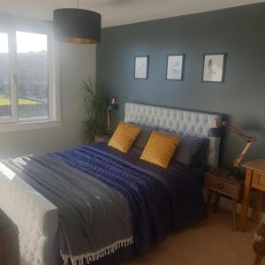 um quarto com uma cama grande com lençóis azuis e almofadas amarelas em Eastwatch guesthouse em Berwick-Upon-Tweed