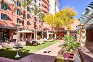 un patio con sillas, mesas y palmeras en Renaissance Phoenix Glendale Hotel & Spa en Glendale