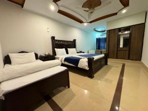a bedroom with two beds and a ceiling at Atlas Gold Hotel in Islamabad