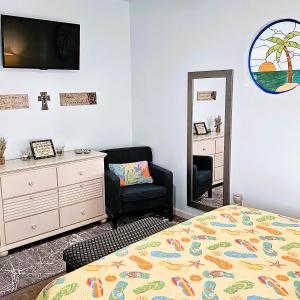 a bedroom with a bed and a chair and a mirror at Aly-Kats Flip Flop Flat in Rockport