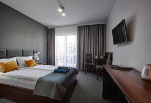 um quarto de hotel com uma cama, uma secretária e uma televisão em Willa MAJA em Krynica-Zdrój