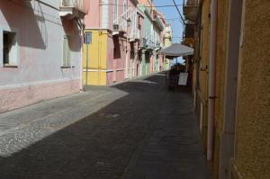 an empty alley with buildings and an umbrella at CaTó - Le vacanze come a casa tua in Carloforte