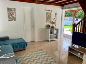 a living room with a couch and a tv at Maison SELAH F3 Piscine Jardin Privatif Citerne in Le Moule