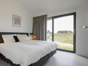 een slaapkamer met een groot bed en een groot raam bij Cottage in Wissenkerke near Banjaard Beach in Wissenkerke