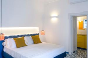 a bedroom with a white bed with two yellow pillows at o' mar - Amalfi Coast Suite in Praiano