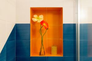 a vase with two flowers on a shelf in a bathroom at o' mar - Amalfi Coast Suite in Praiano