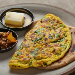a omelet on a plate next to a bowl of butter at Atlas Gold Hotel in Islamabad