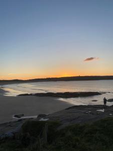 a person standing on the beach at sunset at Village Way Apartments in Kincasslagh