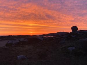 a sunset on a hill with rocks in the foreground at Village Way Apartments in Kincasslagh