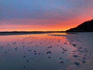 a sunset over a beach with rocks in the water at Village Way Apartments in Kincasslagh