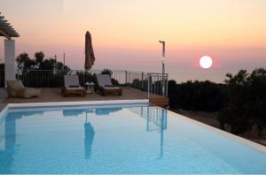 a swimming pool with the sunset in the background at Tsakmakis Villas Luxury- Panoramic Sea View - Lefkada in Tsoukaladhes