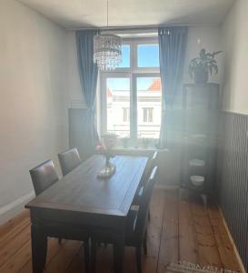 d'une salle à manger avec une table, des chaises et une fenêtre. dans l'établissement City Apartment, à Lübeck