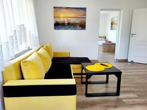 uma sala de estar com um sofá amarelo e uma mesa em Dom na Błękitnej em Karwieńskie Błoto Pierwsze