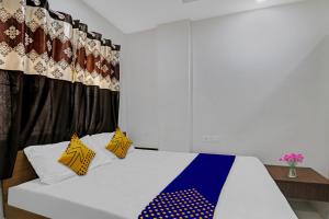 ein Schlafzimmer mit einem weißen Bett mit gelben und blauen Kissen in der Unterkunft OYO Zois Nest in Kammasandra
