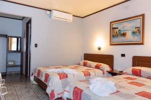 um quarto de hotel com três camas num quarto em Hotel Arenal Rabfer em La Fortuna