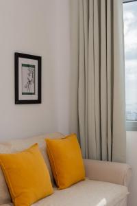 Cozy Residence في مدينة أستيباليا: غرفة معيشة مع أريكة مع وسائد صفراء