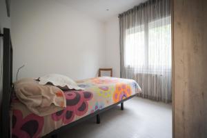 ein Schlafzimmer mit einem Bett mit einer bunten Decke und einem Fenster in der Unterkunft El Solell de l'àvia in Olot