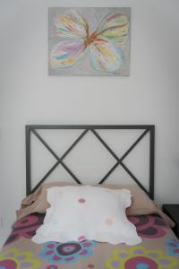 una cama con una pintura de mariposa en la pared en El Solell de l'àvia, en Olot