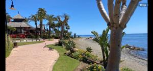 a walkway next to a beach with palm trees at Luxury 3 bed Duplex Penthouse, 3 mins walk to the beach in Estepona