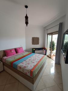 a bedroom with a bed with pink pillows at Appartement de vacances BERALMAR CHEZ HOUDA in Asilah