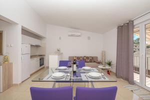 sala de estar con mesa de comedor y sillas moradas en Apartments Nina M en Baška Voda