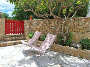 duas cadeiras sentadas em frente a uma parede de pedra em Casa das Janelinhas - Cottage near Sintra, Mafra, Ericeira em Mafra