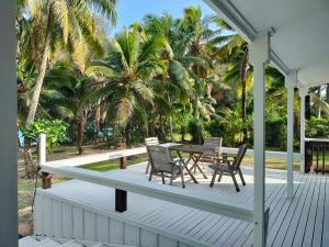 a porch with a table and chairs and palm trees at Oronga Beach in Arorangi