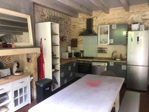 una cucina con tavolo e frigorifero di Le Cottage de Laugère - Gite avec piscine a Charenton sur Cher