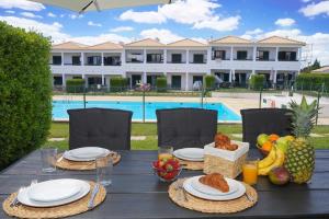 a table with food and fruit on it with a pool at Casa Santos in Albufeira