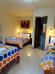 a room with three beds with orange and blue at La Casa de Cecilia Mindo in Mindo