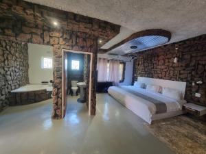 ein Schlafzimmer mit einem Bett und einer Steinmauer in der Unterkunft Rustiek Hotel in Kasane