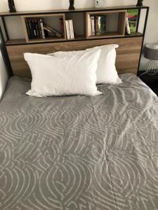 Bett mit einem weißen Kissen und einem Kopfteil aus Holz in der Unterkunft Maisonnette au calme in Gennevilliers