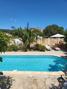 a blue swimming pool with two chairs and an umbrella at Maison Fruitier with pool at 15m from the Beach in Sainte-Maxime