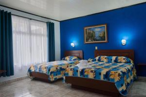um quarto azul com 2 camas e uma janela em Hotel Arenal Rabfer em La Fortuna