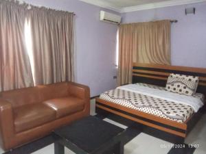 a bedroom with a bed and a leather chair at The Residence in Uyo