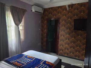a bedroom with a bed and a wall with a television at The Residence in Uyo