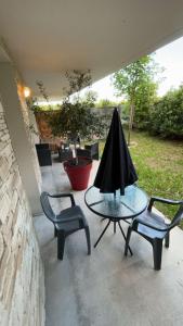 un patio con 2 sillas y una mesa con sombrilla en Suite jacuzzi "spa privatif " appartement Jacuzzi, en Toulouse