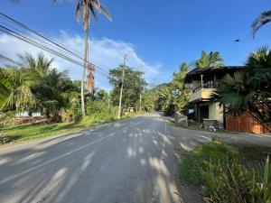 an empty street with a house and palm trees at Perla Negra Beachfront in Puerto Viejo
