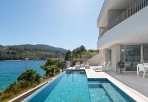 une maison avec une piscine à côté de l'eau dans l'établissement Luxury & stylish Villa Lavanda 5 m from the sea, à Vela Luka