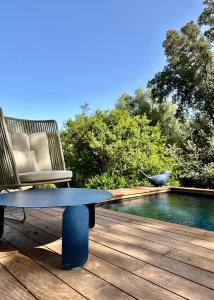 une chaise et une table sur une terrasse à côté d'une piscine dans l'établissement Les Bergeries de Figari, à Figari