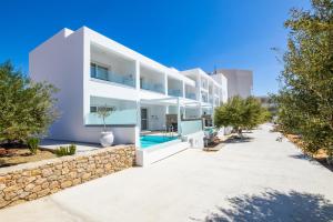 a large white building with a pool and trees at Alkithea luxury suites in Karpathos Town