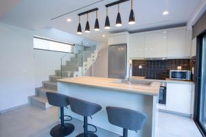 a kitchen with a counter with two chairs and a sink at Mylos ridge villas - ORION in Agios Nikitas