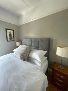 een slaapkamer met een groot bed met witte lakens en kussens bij Grey Heron Townhouse in Newcastle