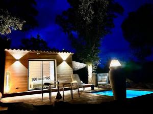 a small house with chairs and a pool at night at Les Bergeries de Figari in Figari
