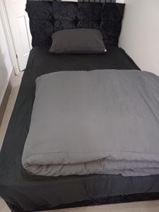 ein großes Bett mit einer grauen Bettdecke und Kissen in der Unterkunft Budgeted Residence near Coventry Building Society (CBS) Arena with Parking in Exhall
