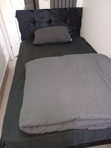 ein Bett mit einer grauen Bettdecke und einem Kissen in der Unterkunft Budgeted Residence near Coventry Building Society (CBS) Arena with Parking in Exhall