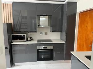 eine Küche mit grauen Schränken, einer Spüle und einer Mikrowelle in der Unterkunft Unit 76 Melville Mews in Johannesburg