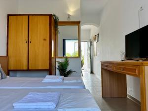 a bedroom with two beds and a desk with a television at Elgreco Apartment, at Tigaki, near the sea "3" in Tigaki