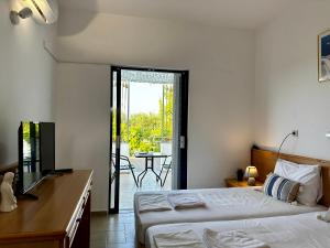 a bedroom with two beds and a balcony with a table at Elgreco Apartment, at Tigaki, near the sea "3" in Tigaki