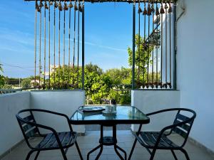 a glass table and two chairs on a balcony at Elgreco Apartment, at Tigaki, near the sea "5" in Tigaki